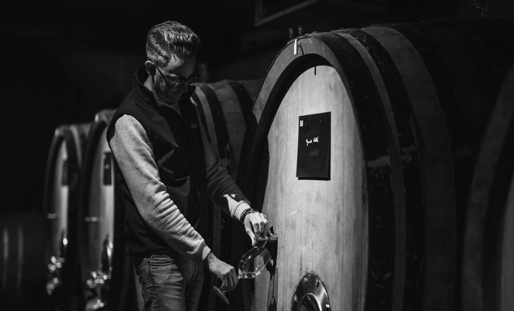Employé vérifiant le vin dans une cuve de bois au sein de la cave de Champagne Jacquesson
